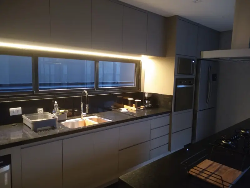 Cozinha com bancada escura e iluminação sob os armários