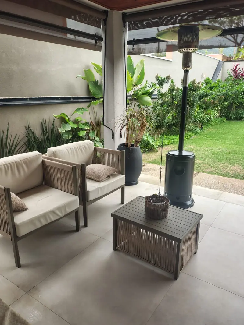 Área gourmet coberta com sofás voltados para o jardim