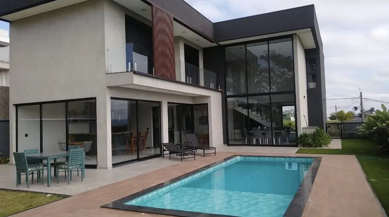 Casa de dois pavimentos com pano de vidro em pé-direito duplo, deck e piscina