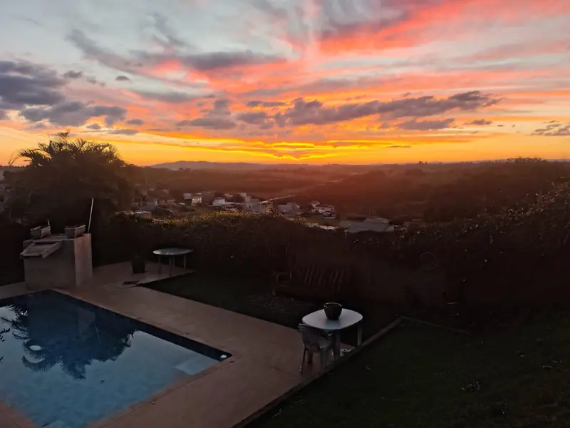 Pôr do sol visto do jardim com piscina