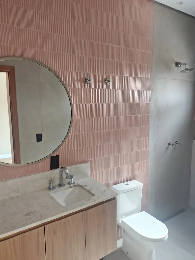 Banheiro com revestimento rosa e espelho redondo