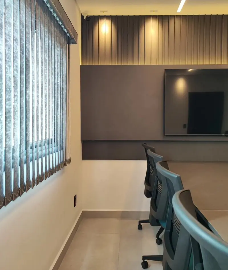 Sala de reunião com painel ripado iluminado e TV