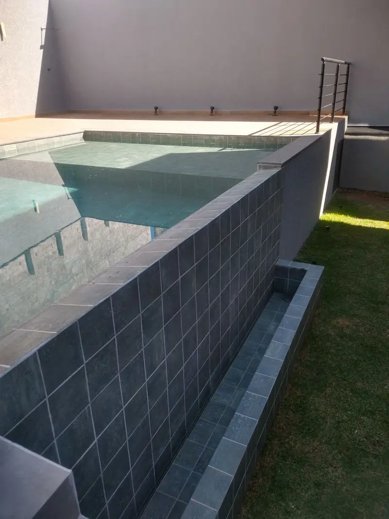 Piscina elevada com borda infinita revestida em pedra