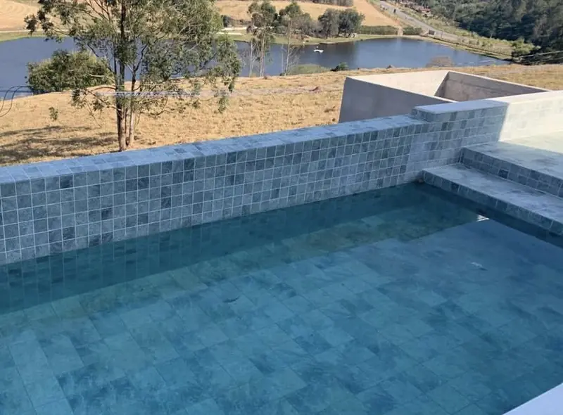 Piscina revestida em pedra com vista para o lago