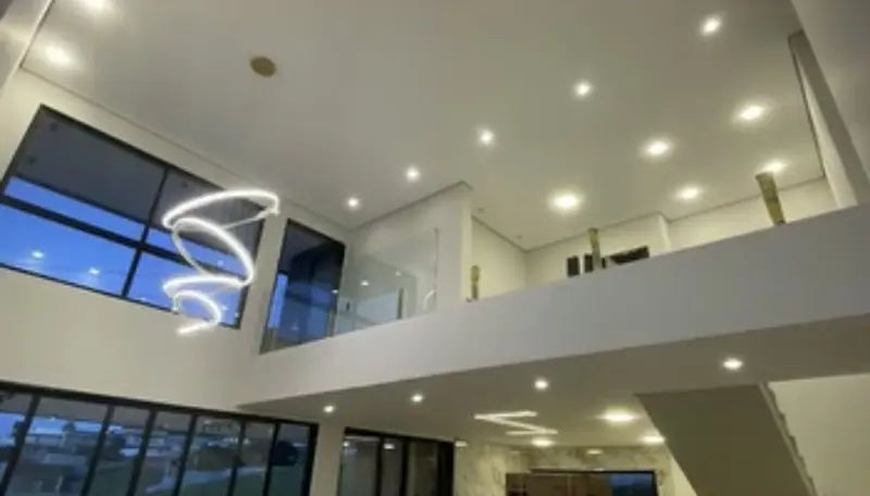 Sala com pé-direito duplo, mezanino e esquadrias de piso a teto