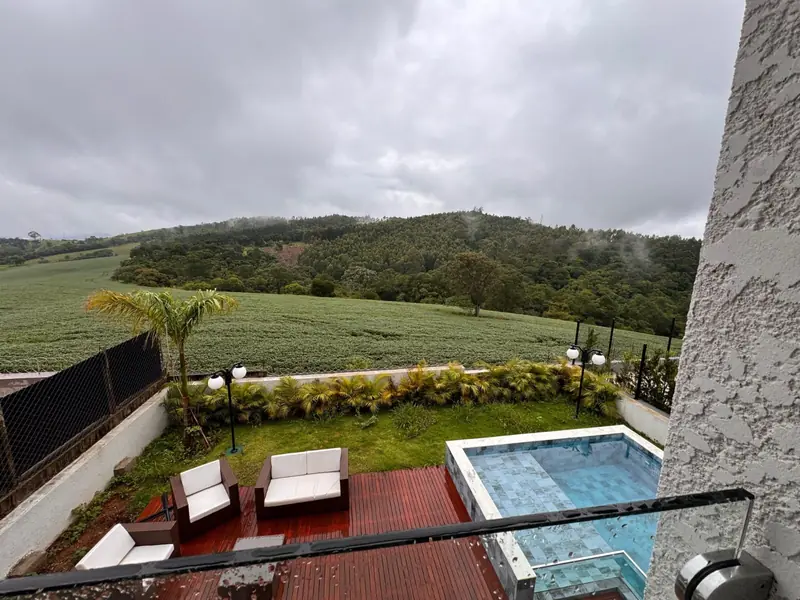 Deck, piscina e jardim vistos do pavimento superior, com montanhas ao fundo