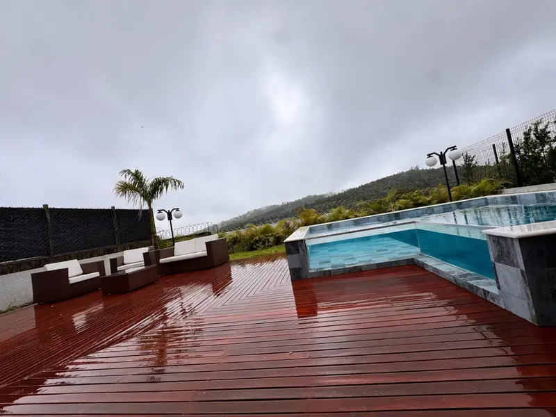 Deck de madeira com sofás e piscina com visor de vidro
