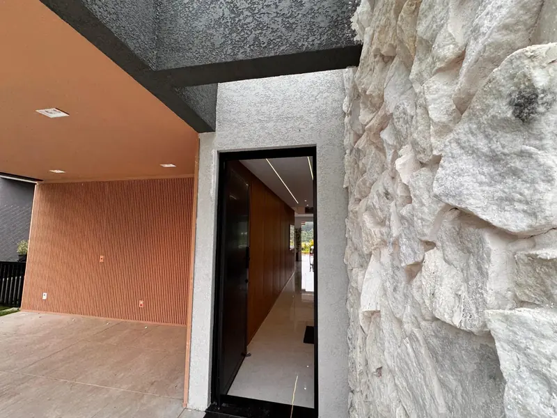Entrada da casa com parede de pedra e painel ripado