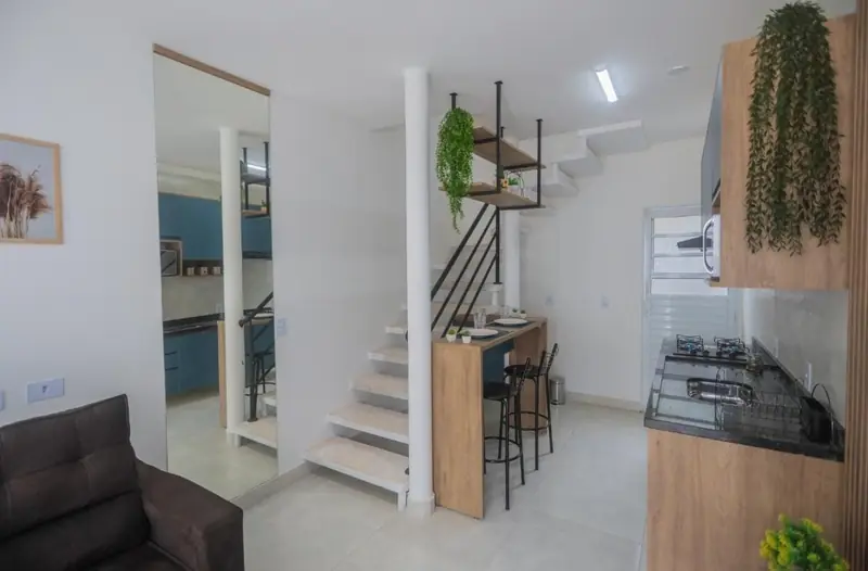 Sala do sobrado com escada, bancada de refeições e cozinha