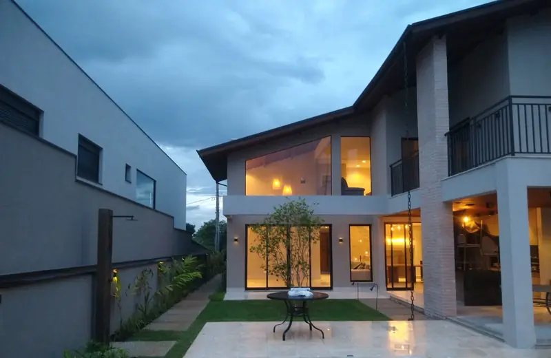 Casa iluminada ao entardecer, com jardim e deck