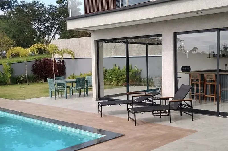 Terraço com espreguiçadeiras e área gourmet ao fundo